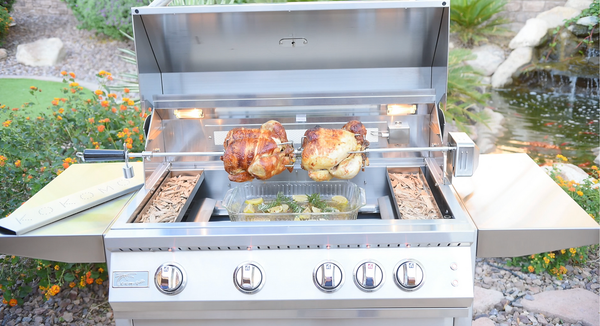 Front view of a KoKoMo grill cooking two rotisserie chickens above a tray of vegetables