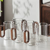Close-up of ergonomic dark walnut wood handle on clear glass mug