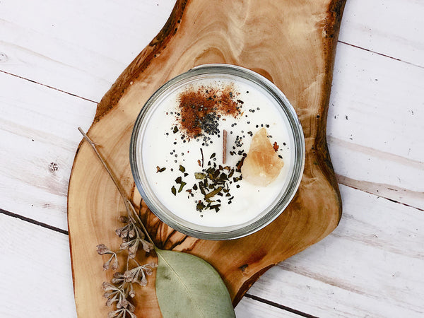 Close-up of ritual candle with dried herbs, citrine crystal, and wood wick, non-toxic soy wax