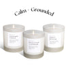 Three candles with labels on a white background, featuring the brand 'Calm + Grounded'