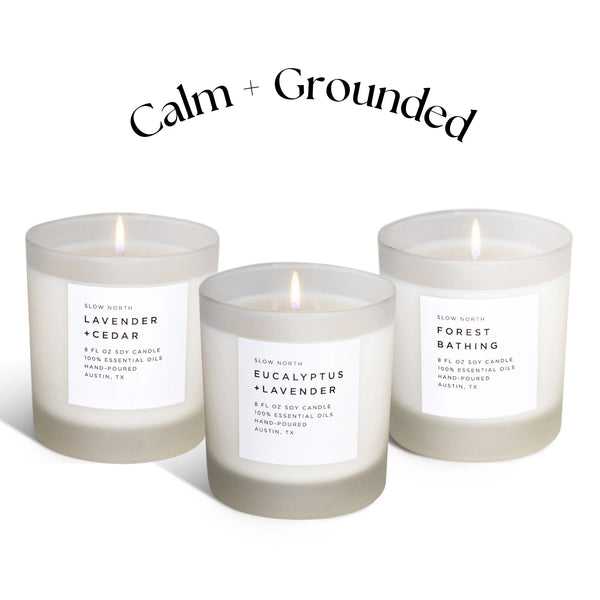 Three candles with labels on a white background, featuring the brand 'Calm + Grounded'