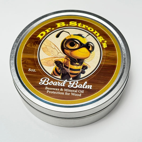 Closed 8 oz tin of Dr. B.Strong’s Board Balm with a bee-illustrated label on a white background