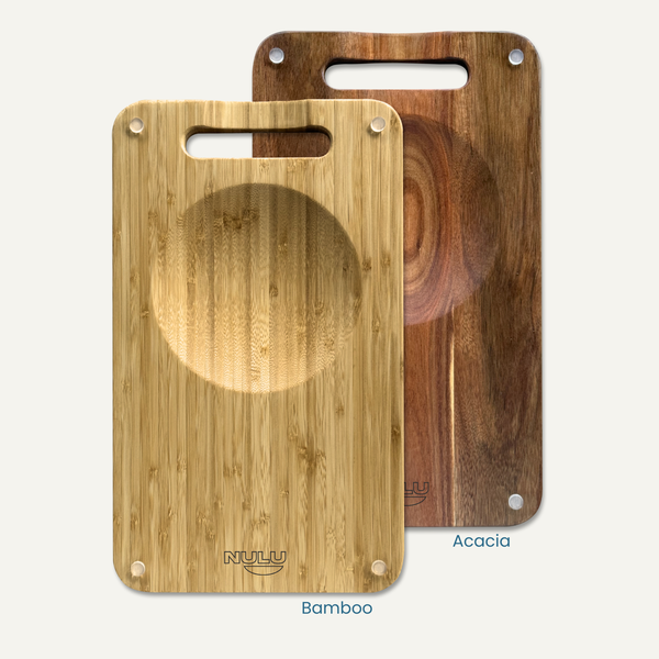 NULU bamboo and acacia cutting boards side by side, each with a recessed mincing bowl and carrying handle