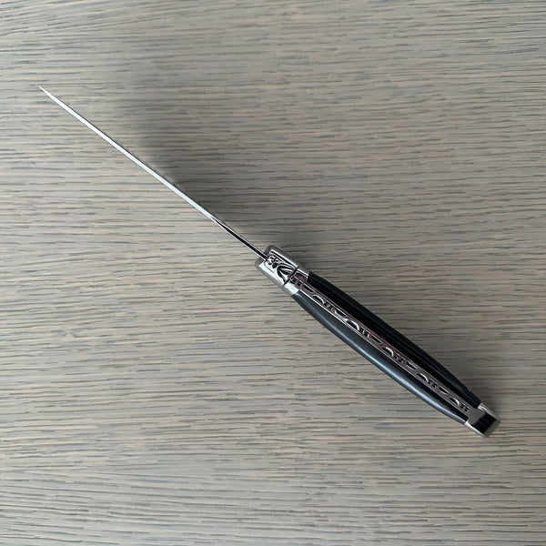 Top view of the ebony-handled pizza knife showing its slim blade profile, bee emblem and decorative metal spine