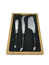 Overhead view of three ebony-handled cheese utensils arranged in a fitted black insert within a wooden tray