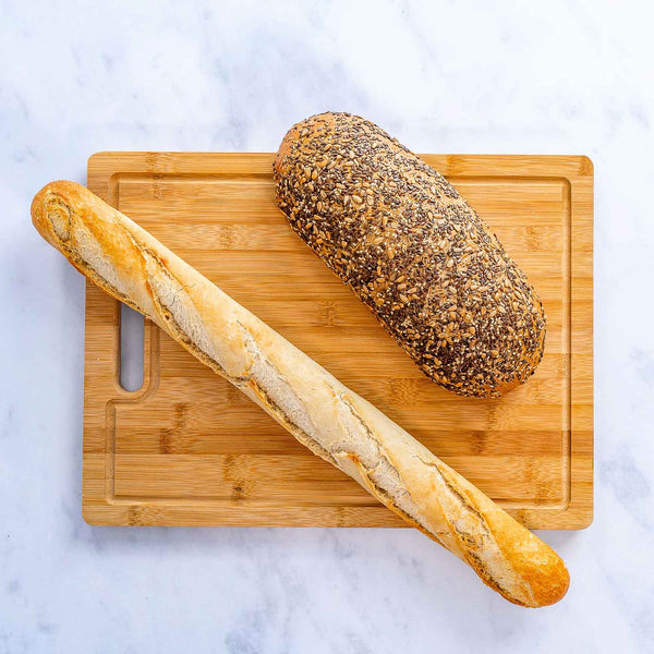 Two loaves of bread on a wooden cutting board with a light background