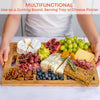 Wooden cutting board with assorted fruits, cheeses, and meats on a white background.
