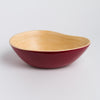 Bowl with red interior and wooden exterior on a light gray background