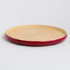 Round plate with red rim and beige center on a light gray background