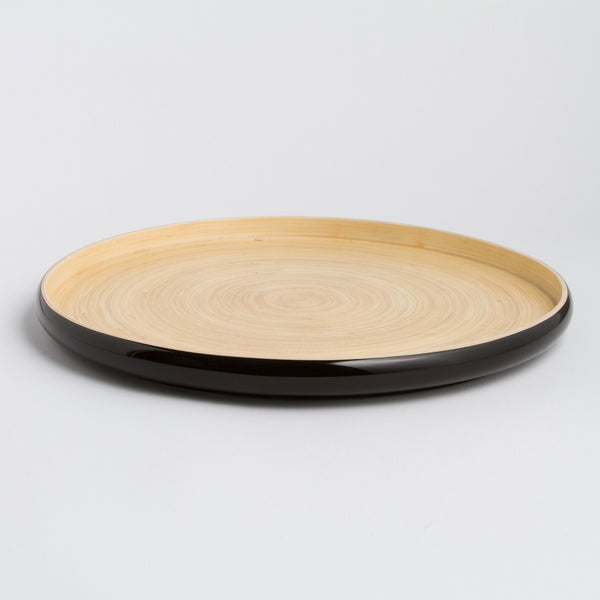 Round bamboo Tray with black rim and beige center on a light gray background