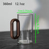 Clear glass mug with wooden handle and measurements on a gray background