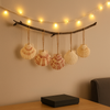 Decorative branch with hanging seashells and string lights against a beige wall.
