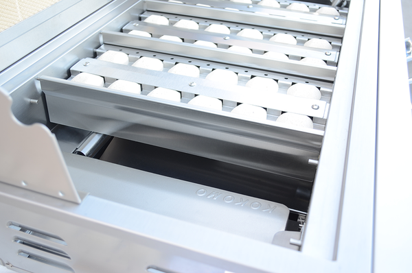 KoKoMo grill interior showing pale briquettes in metal trays above the burners