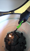 Gloved hand using a long lighter to ignite charcoal inside the KoKoMo ceramic Kamado grill