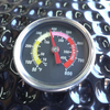 Close-up of the Kamado lid thermometer with Fahrenheit and Celsius scales and marked cooking zones