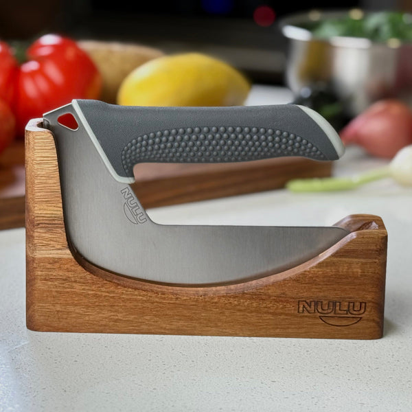 NULU kitchen knife seated in an acacia wooden dock on a kitchen counter with vegetables behind it