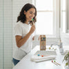 Four natural bamboo toothbrushes neatly arranged on a minimalist bathroom shelf