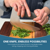 Person using both hands on the NULU knife handle to rock the curved blade through fresh herbs on a wooden board