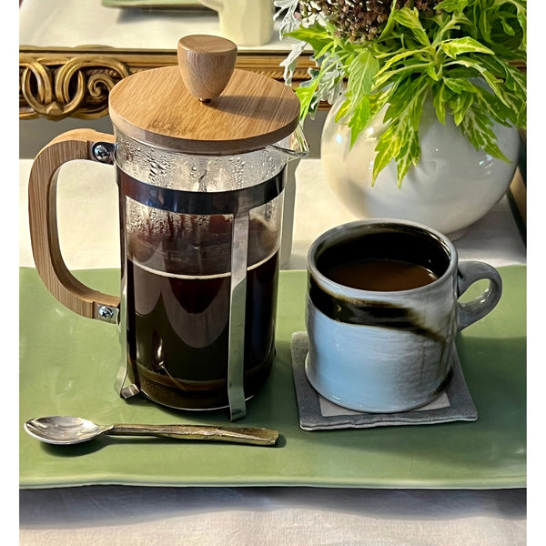 "Classic French Press coffee maker filled with fresh, rich coffee on a rustic table"