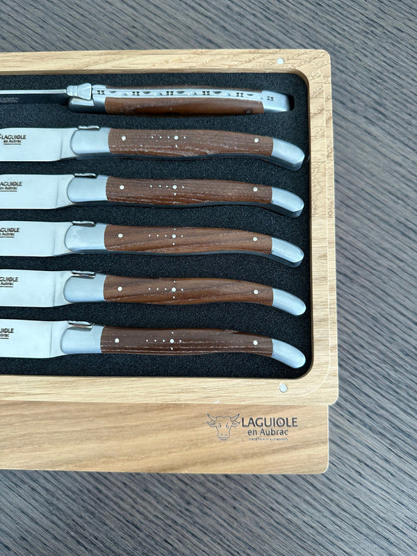 Close-up of six ash wood knife handles in their presentation box, showing metal rivets, Shepherd’s Cross details and matte steel bolsters