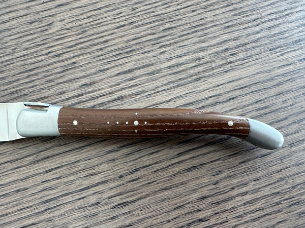 Laguiole en Aubrac ash wood handle showing natural grain, Shepherd’s Cross rivets and matte steel bolsters