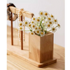 Wooden vase with white flowers on a wooden surface