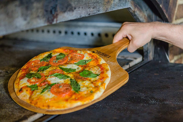 Bamboo pizza peel sliding a fresh artisanal pizza into the oven, heat-resistant wooden kitchen tool