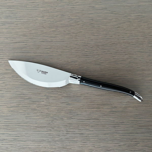 Laguiole en Aubrac pizza knife with a broad curved serrated blade and ebony handle on a gray wooden surface