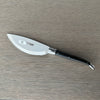 Laguiole en Aubrac serrated pizza knife with an ebony wood label on the blade, resting on a gray wooden surface