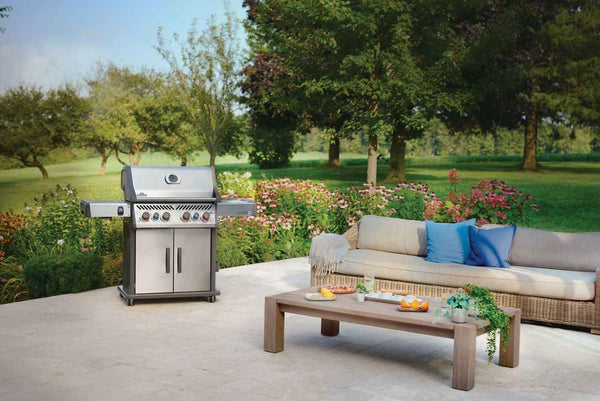 Napoleon Rogue PRO-S 525 grill beside outdoor seating and a coffee table on a garden patio