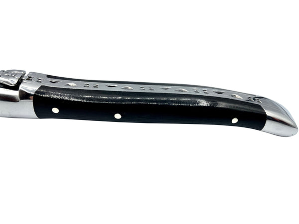 Side view of an ebony cheese knife handle with three metal rivets, polished end cap and decorative spine