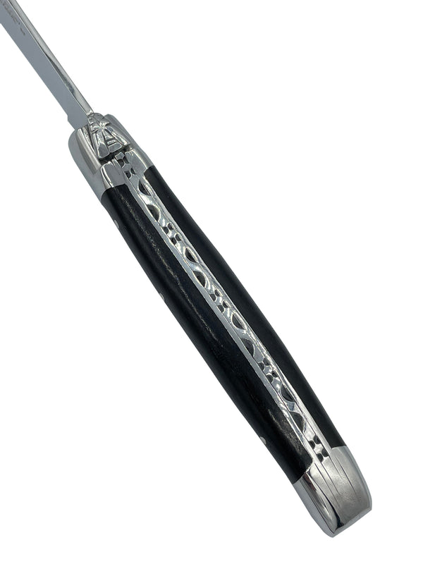 Close-up of a Laguiole en Aubrac ebony handle showing decorative metal spine detailing and the bee emblem