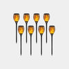 Set of solar-powered flame-tipped garden lights on a white background