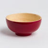 Red ceramic bowl with a beige interior on a light gray background