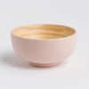 Pink ceramic bowl with wooden interior on a light gray background