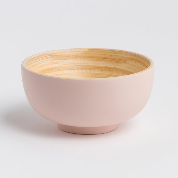 Pink ceramic bowl with wooden interior on a light gray background