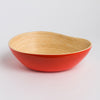 Bowl with red exterior and natural wood interior on a light gray background