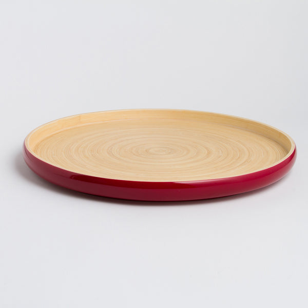 Round plate with red rim and beige center on a light gray background