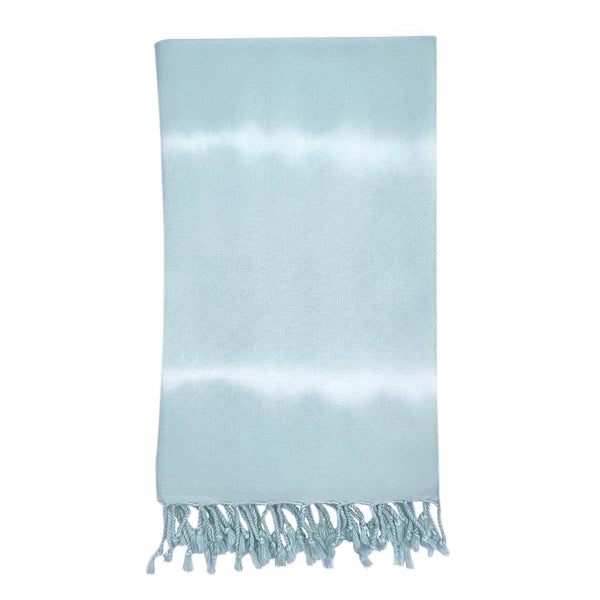 Ocean tie dye Turkish beach towel with hand-knotted tassels laid out on sand