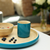 Teal mug and bowl with berries on a matching tray in a home setting