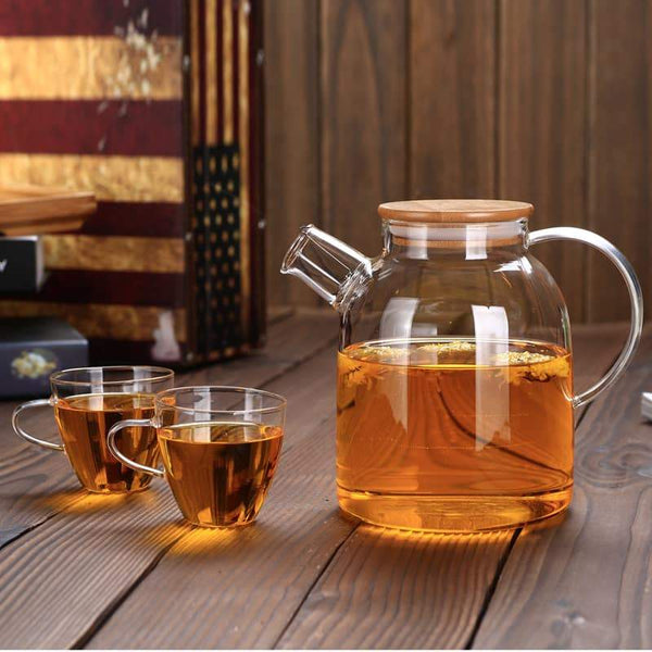 Minimalist glass teapot styled with tea cups in a sunlit kitchen"