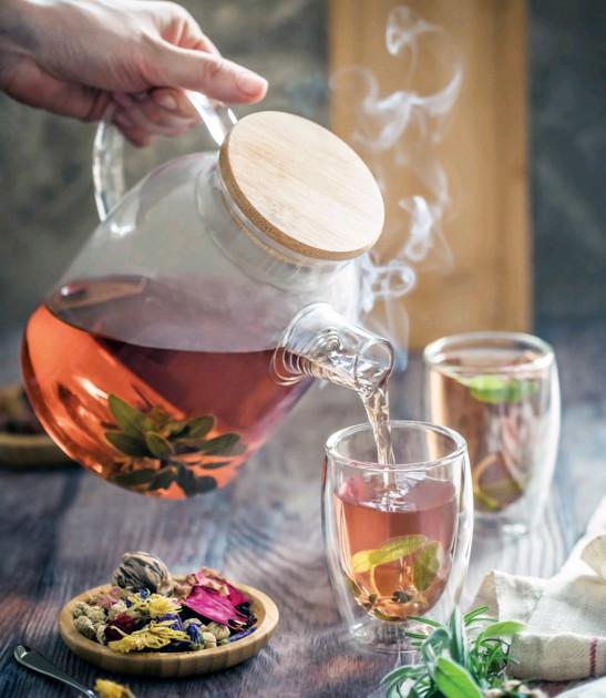 Thermo Glass Teapot filled with blooming herbal tea on a wooden tray